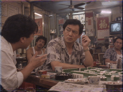 Brother Tat listens skeptically at a mahjong table